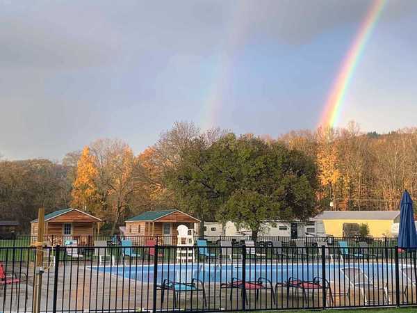 Photo of pool area with a double rainbow in the background at Trout Run Camp Resort. 