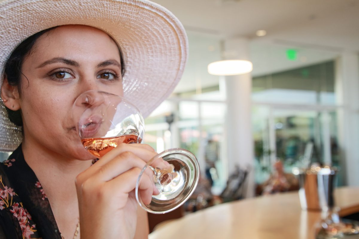 A woman samples a wine tasting or rosé.