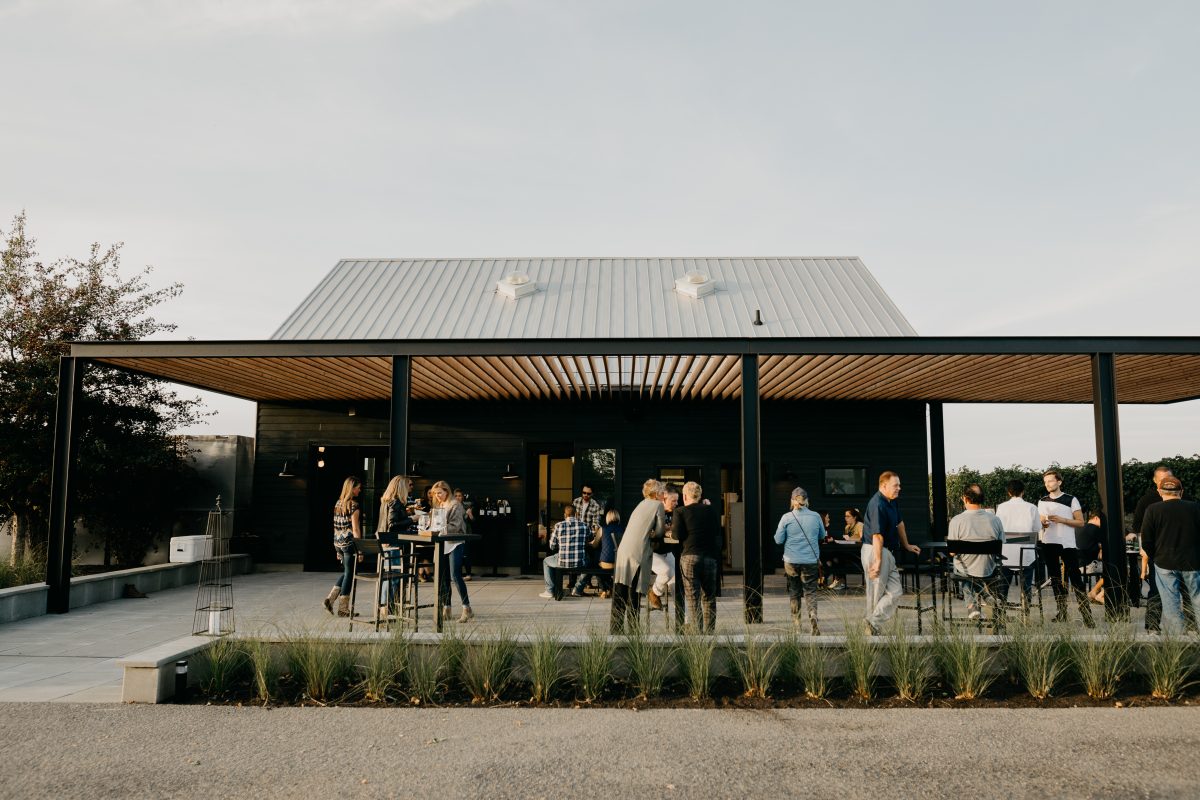 Guests stand and converse on the patio of KINHAVEN Winery in Walla Walla, WA.