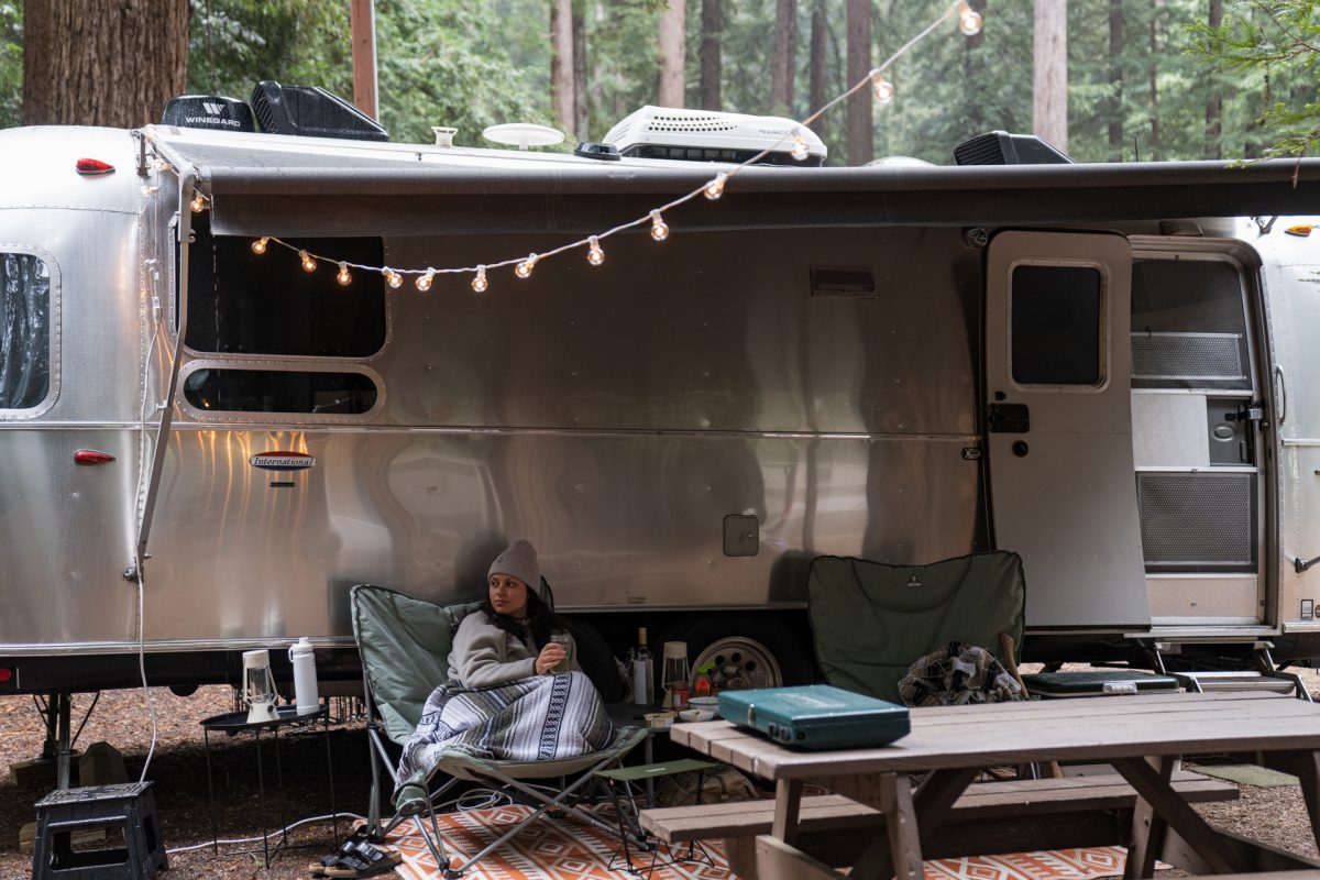 A woman enjoys a glass of wine at her campsite in front of her Airstream trailer at the Santa Cruz Redwoods RV Resort in Felton, California.