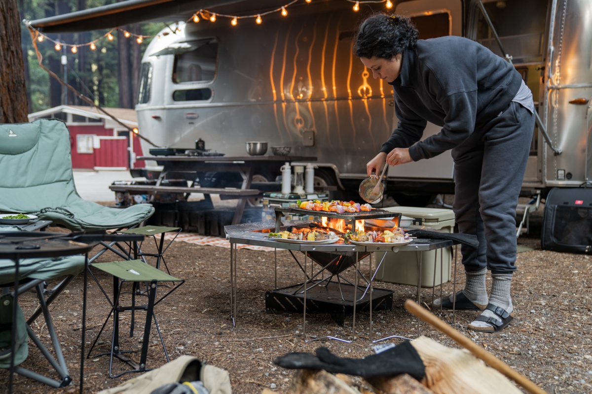 A camper prepares screwers on a Snow Peak campfire.