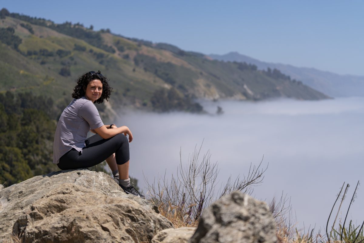 A woman looks out to the cloud covered ocean in Big Sur, CA.