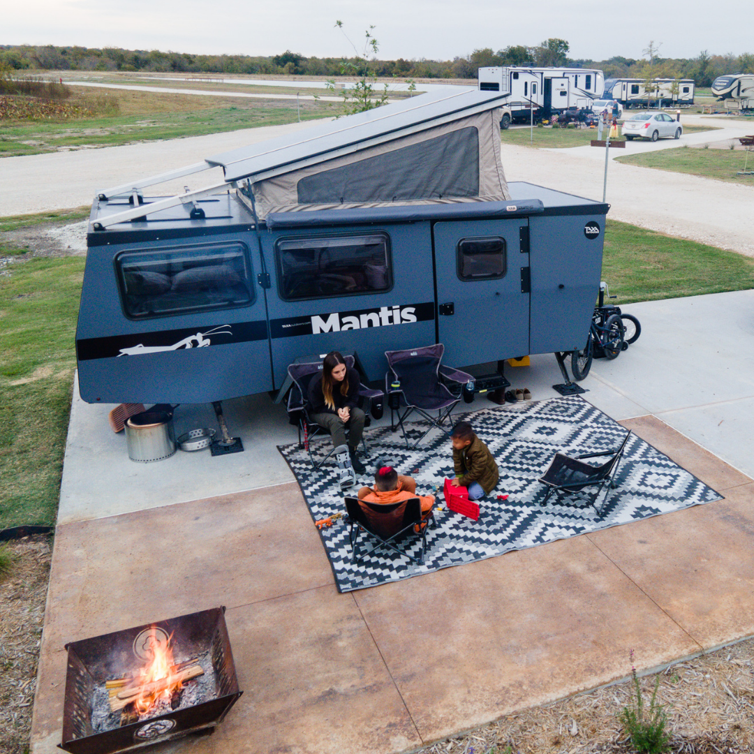 mom with kids sitting next to RV at campground.