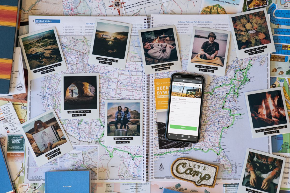 Miscellaneous camping pamphlets, travel guides, cell phone, and photographs on top of a map of the United States of America. 