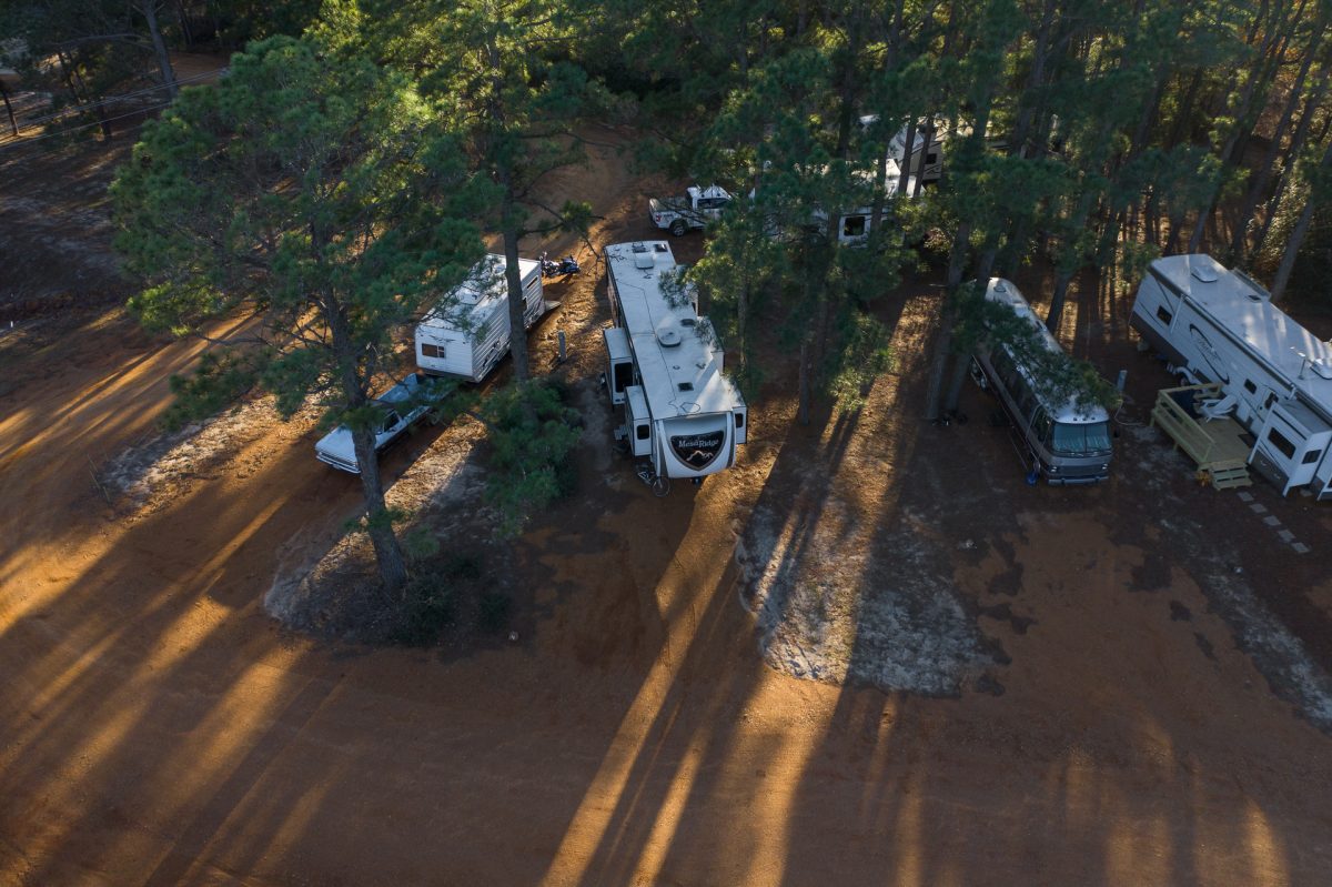 RVs parked in tree-covered campsites at The Pines at Bastrop RV Park in Bastrop, Texas.