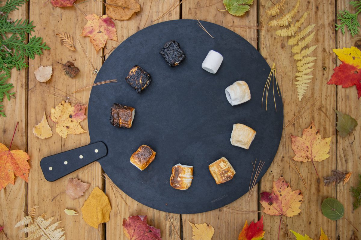 A spectrum of roasted marshmallows sit on a cutting board, arranged in a circle. This shows the variety of options people like when they make s'mores.