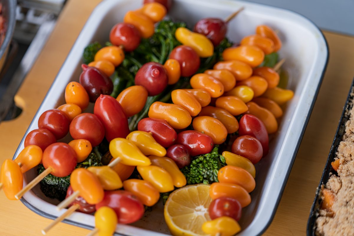 Skewered cherry tomatoes slightly coated with olive oil and on top of broccolini. 