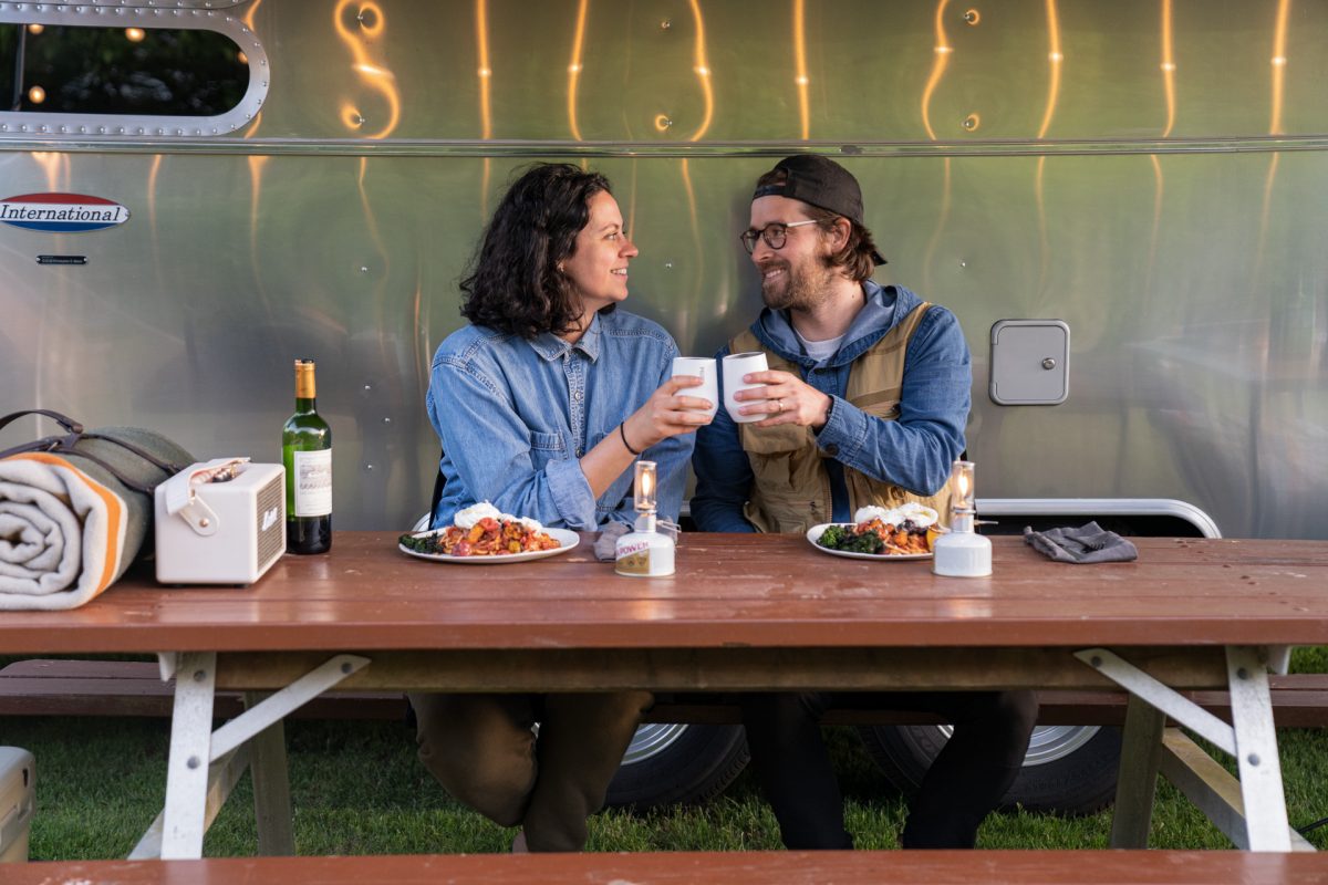 A couple cheers before digging into a plate of campfire roasted tomato pasta with burrata and broccolini. 