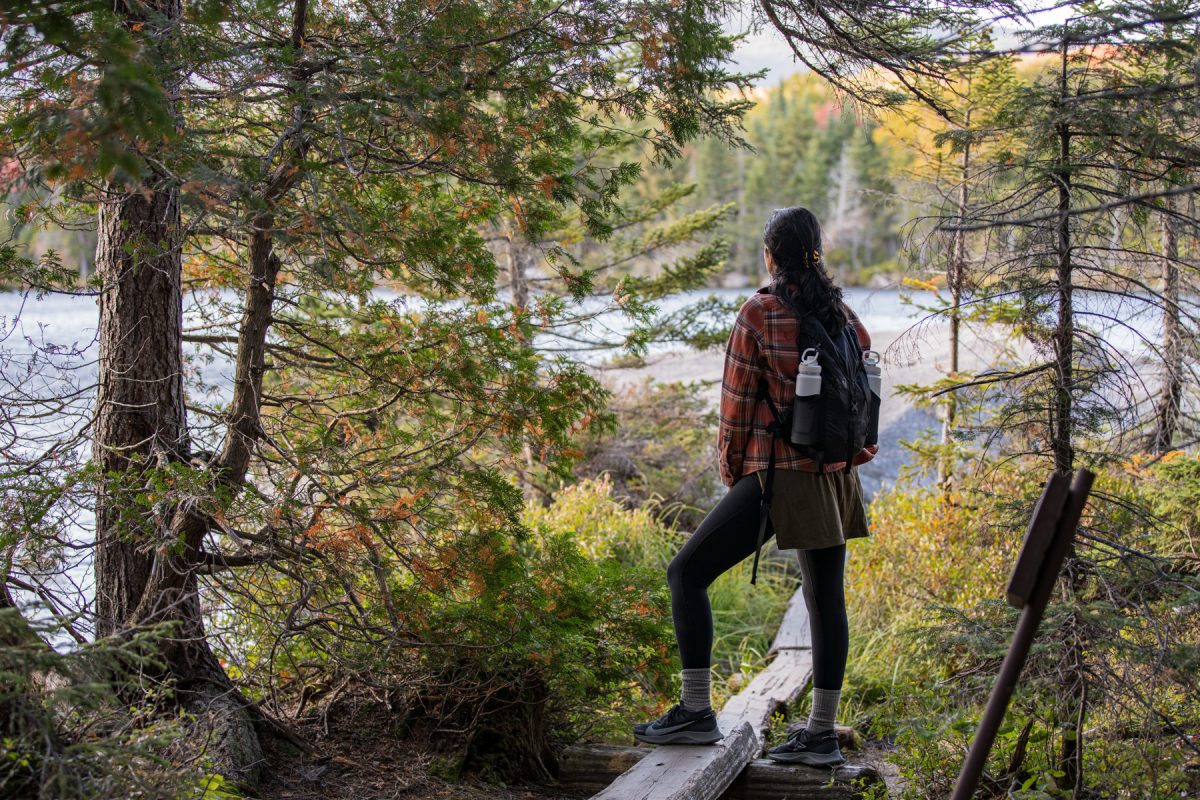 A woman hikes the Sandy Stream Pond Trail in Baxter State Park and overlooks the pond in the distance.