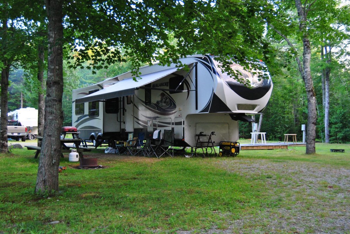 A fifth-wheel travel trailer parked in an RV campsite at Forest Ridge Campground in Ellsworth, Maine.