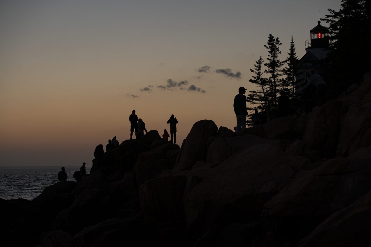 The silhouette of sunset watchers at Bass Harbor Head Lighthouse in Acadia National Park, Maine.