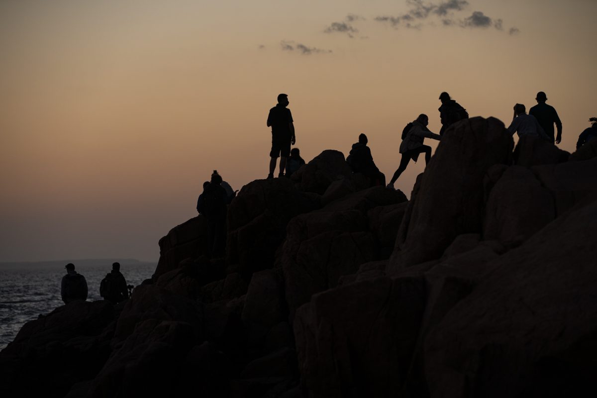 Sunset watchers climb the rocks at Bass Harbor Head Lighthouse in Acadia National Park, Maine.