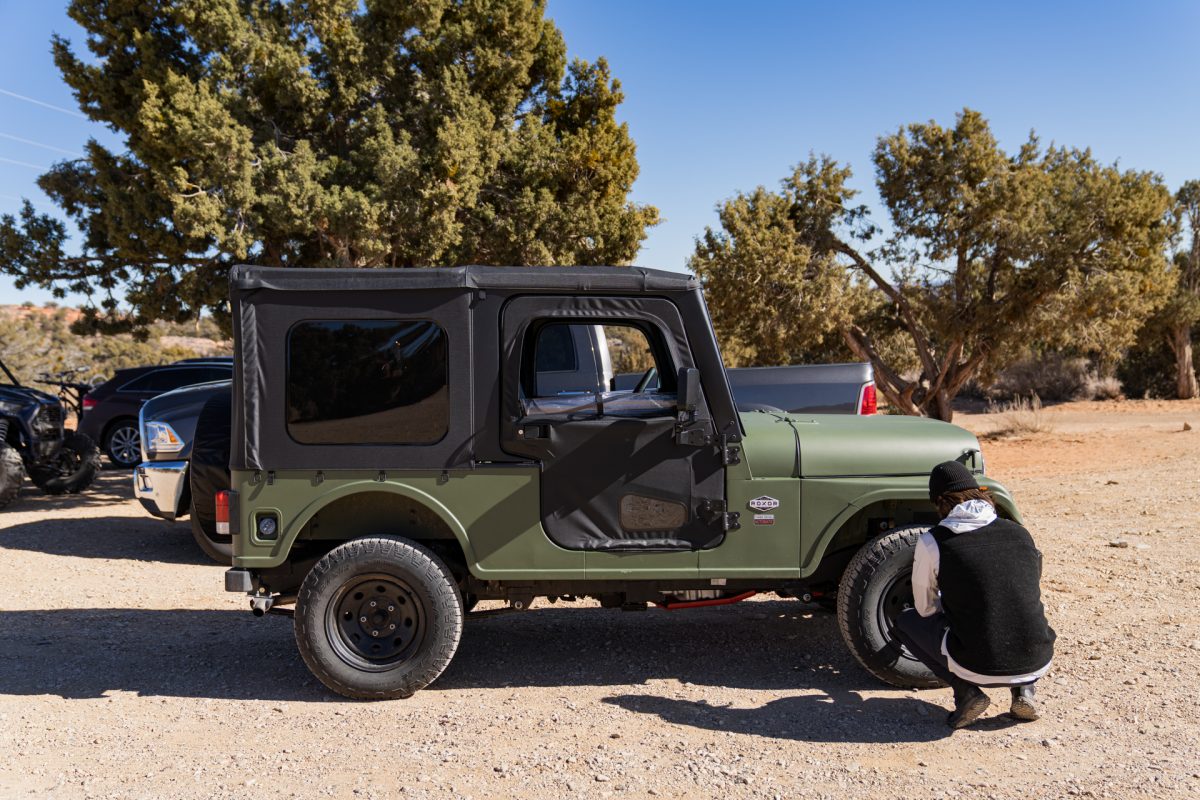 A man deflates the tire on a ROXOR off-road vehicle in the staging area of the Peek-a-boo slot canyon trail.