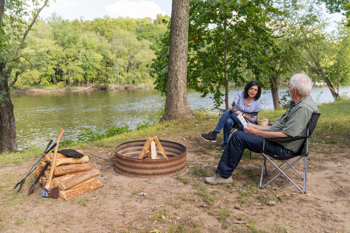 A traveling Snowbird or Winter Texan couple sit near their campfire, looking at the Campspot app.