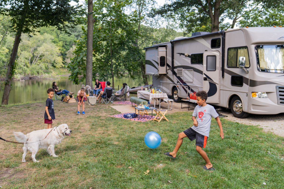 A dog playing with children at a campsite.