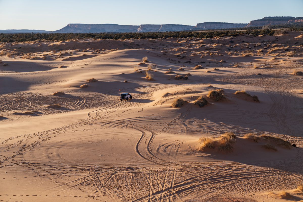 A jeep drives on the dunes at Coral Pink Sand Dunes State Park, one of the best things to do in see in Kanab, Utah.