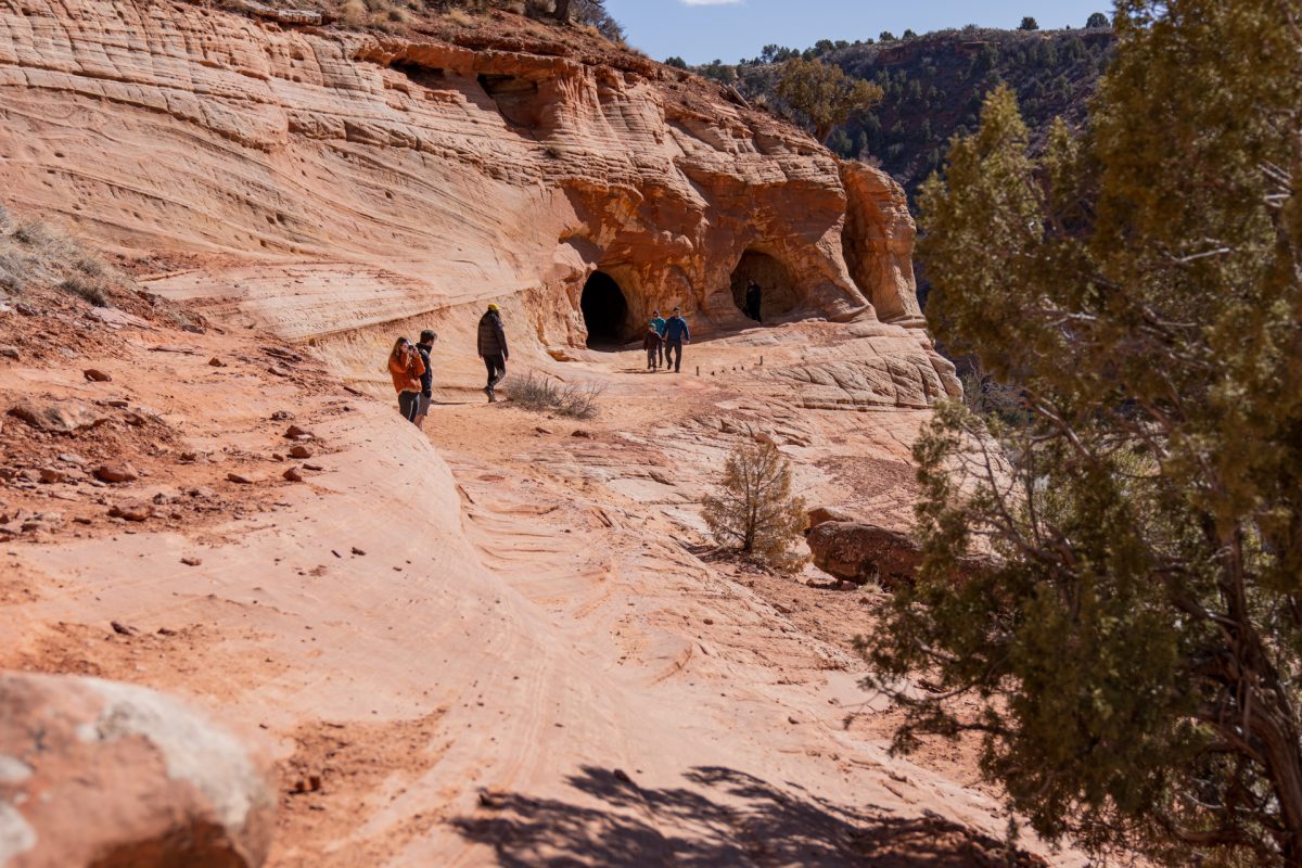 Visitors approach sand caves made out of sandstone. The sand coves are one of the most popular things to do when visiting Kanab, Utah.