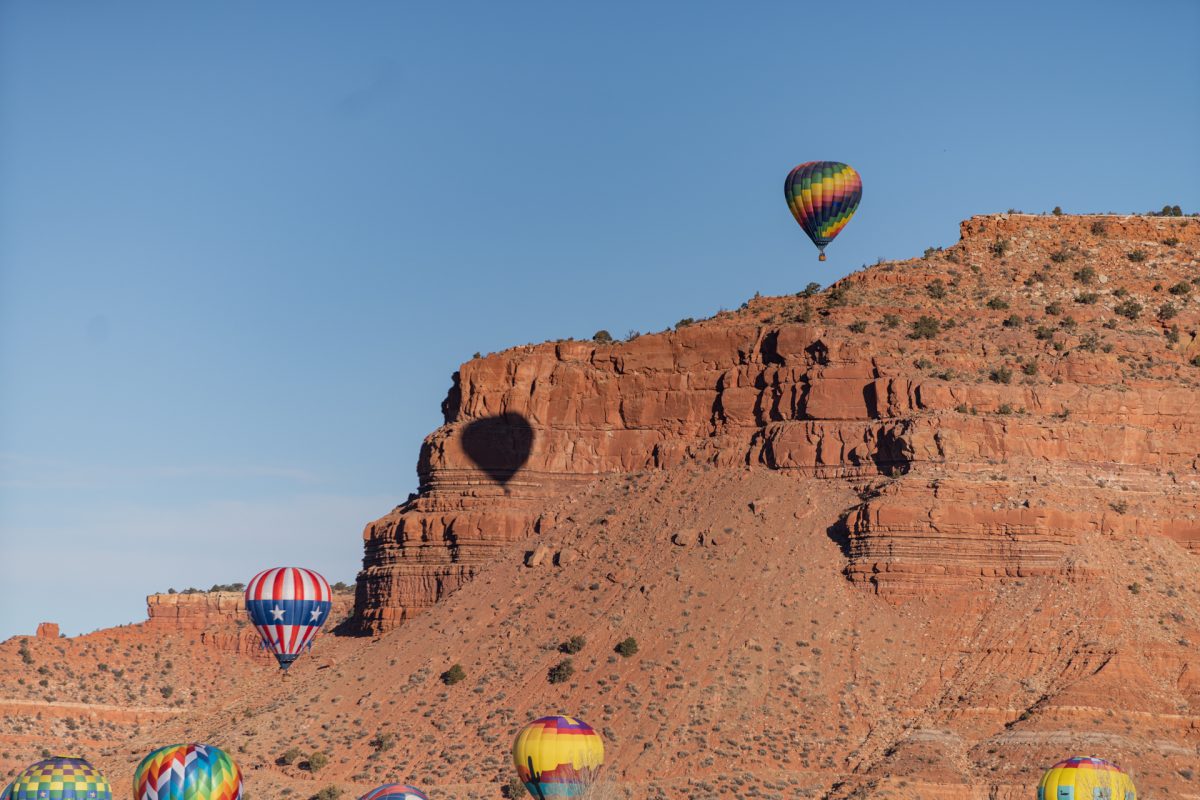 Hot air balloons from the Balloons and Tunes Roundup in Kanab, Utah, float in sky against the Vermillion cliffs.