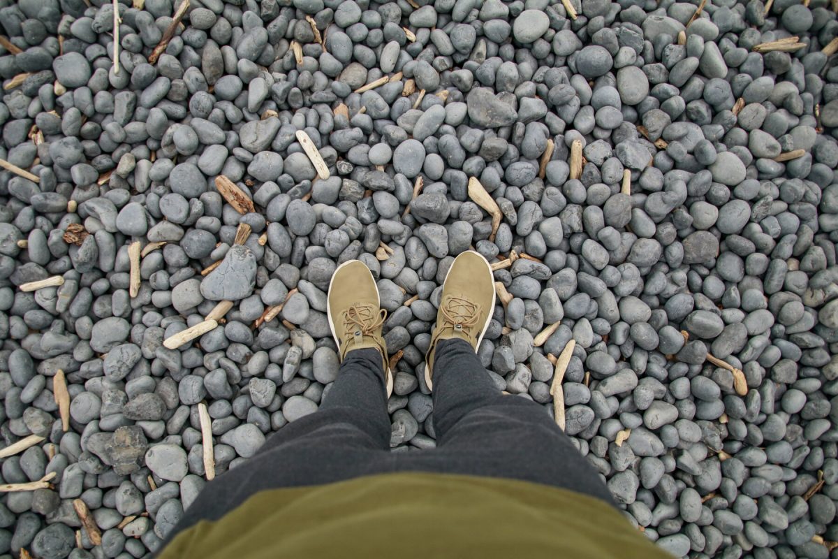 A person looks down to the round black stones seen at the Yaquina Head Garden along the Oregon Coast, a popular Oregon camping destination. 