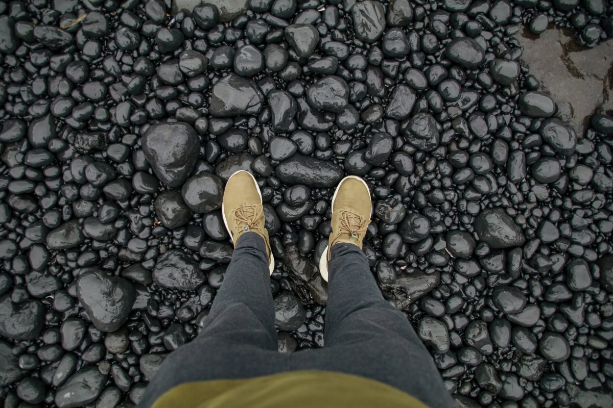 A person looks down to the round black stones seen at the Yaquina Head Garden along the Oregon Coast, a popular Oregon camping destination. 