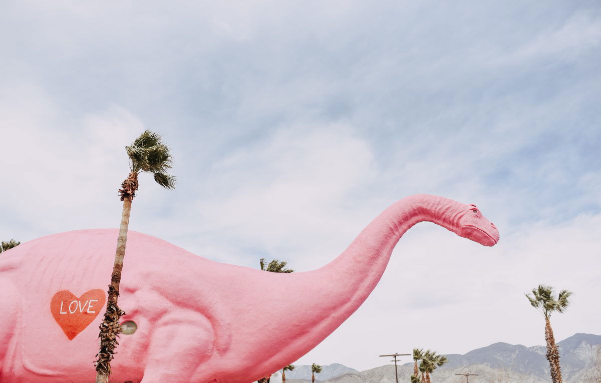 Palm Springs Pink Dinosaur next to palm trees