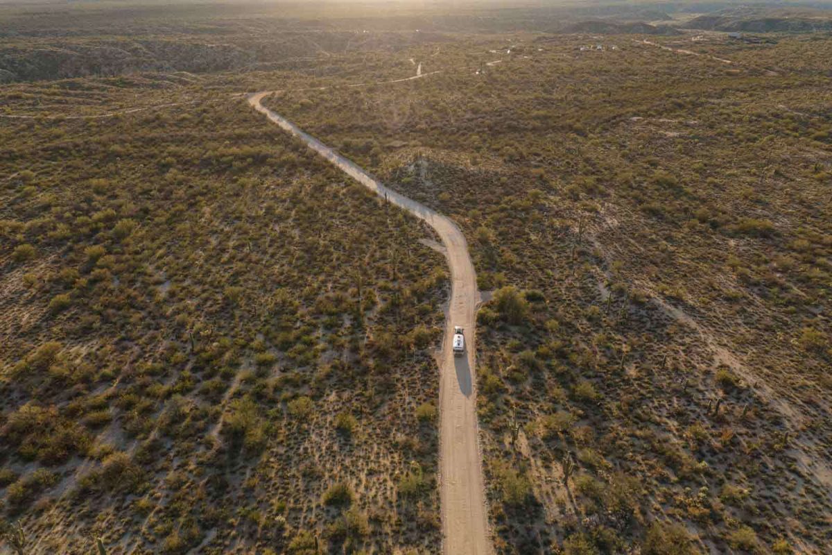 A truck pulls a camper down a remote desert road. 