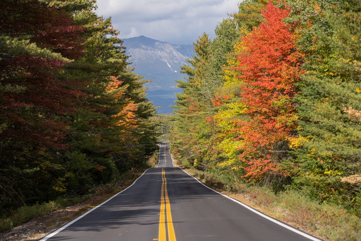 Open road in Maine surrounded by trees with a mountain in the distance. Nary a billboard in sight. 