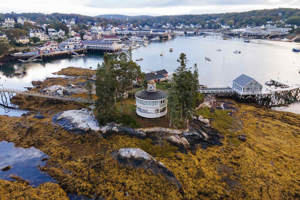 Boothbay coastline in Maine. Boats float in the waters outside of Boothbay with docks lining the shore. 