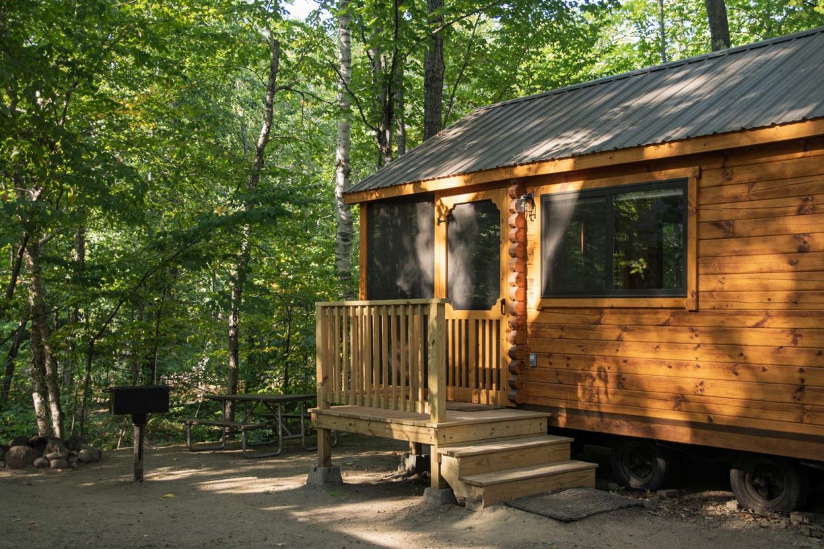 A log cabin with a small front porch surrounded by trees. 