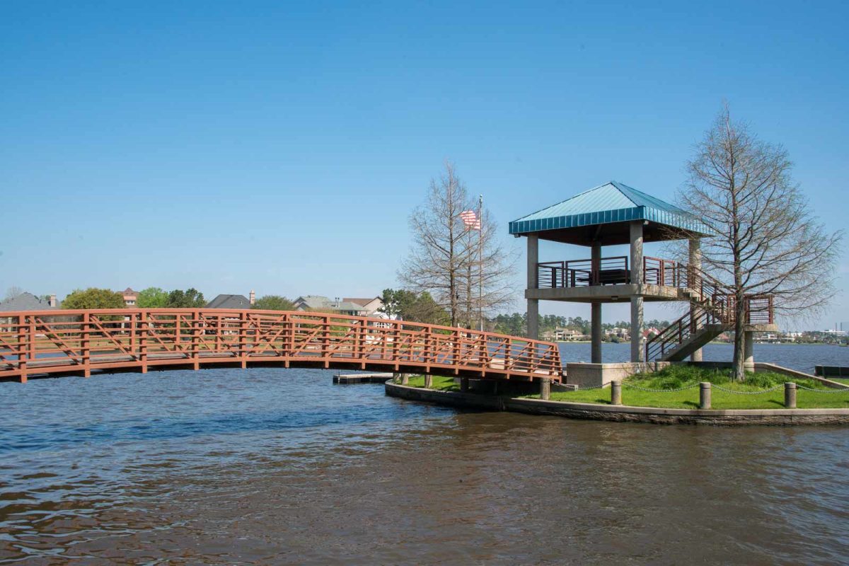 Lake Woodlands is a favorite for fans of outdoor activities in Houston. A bridge connects to a small island with water beneath. 