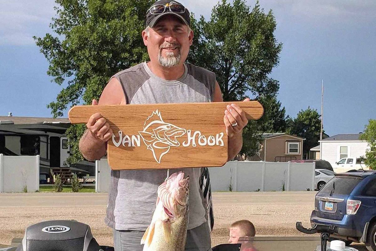 A man holds a Van Hook sign with a fish attached at Van Hook Resort. 