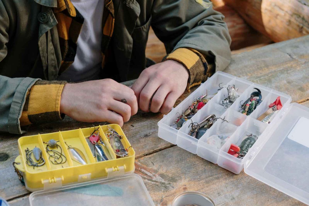 A person seated at a table, stocking a tackle box for fishing. 