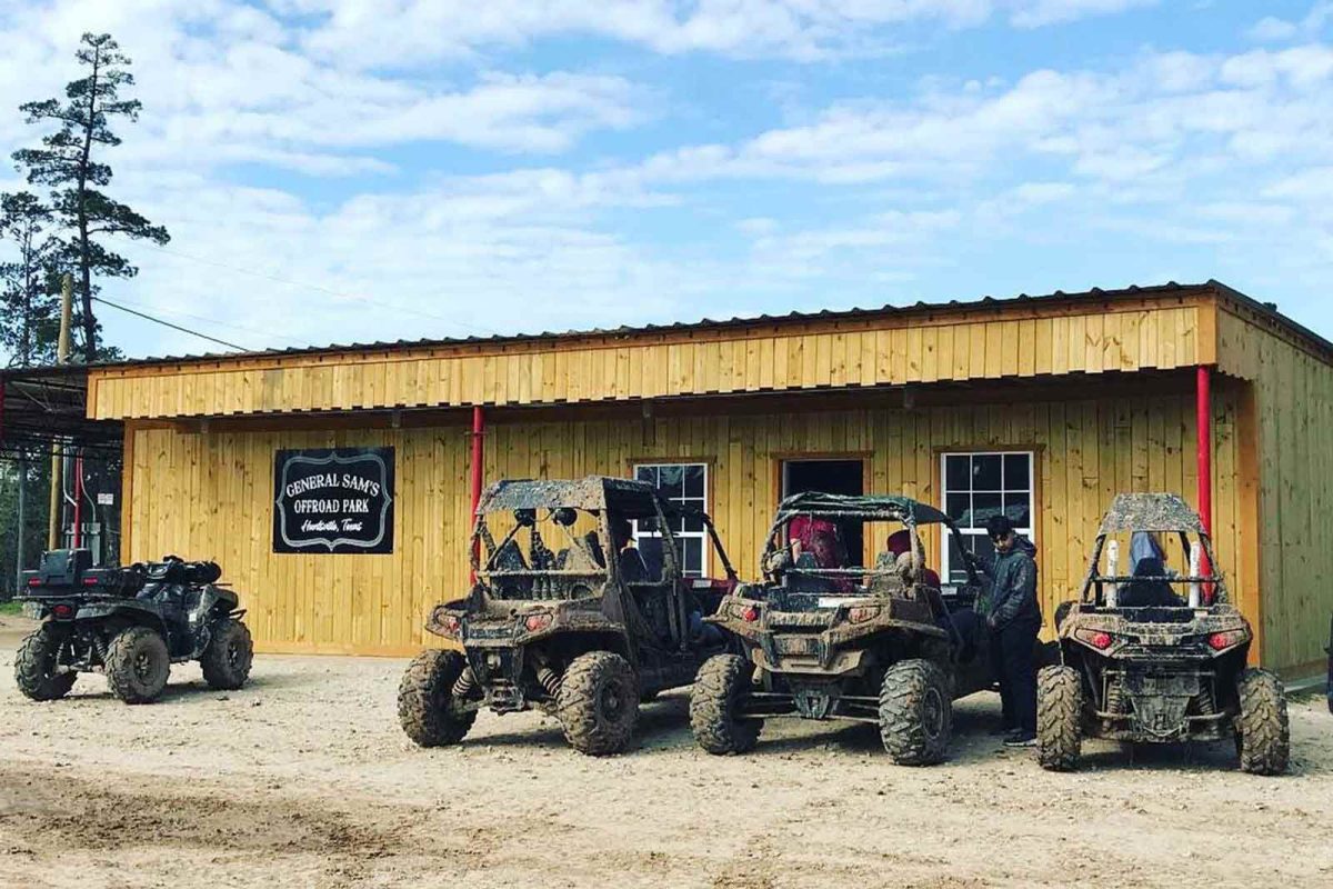 Four muddy ATVs parked outside of General Sam's Offroad Park. 