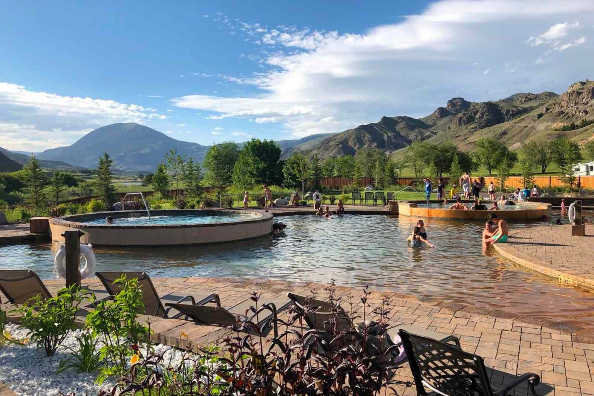 Campers enjoy hot spring pools at Yellowstone Hot Springs with mountain views in the distance. 