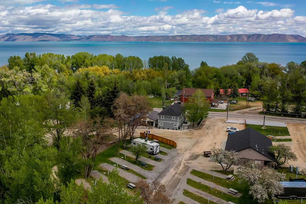 An aerial shot of campgrounds at Bear Lake Venture Park. Campsites are surrounded by trees and the lake and mountains are visible along the horizon. 