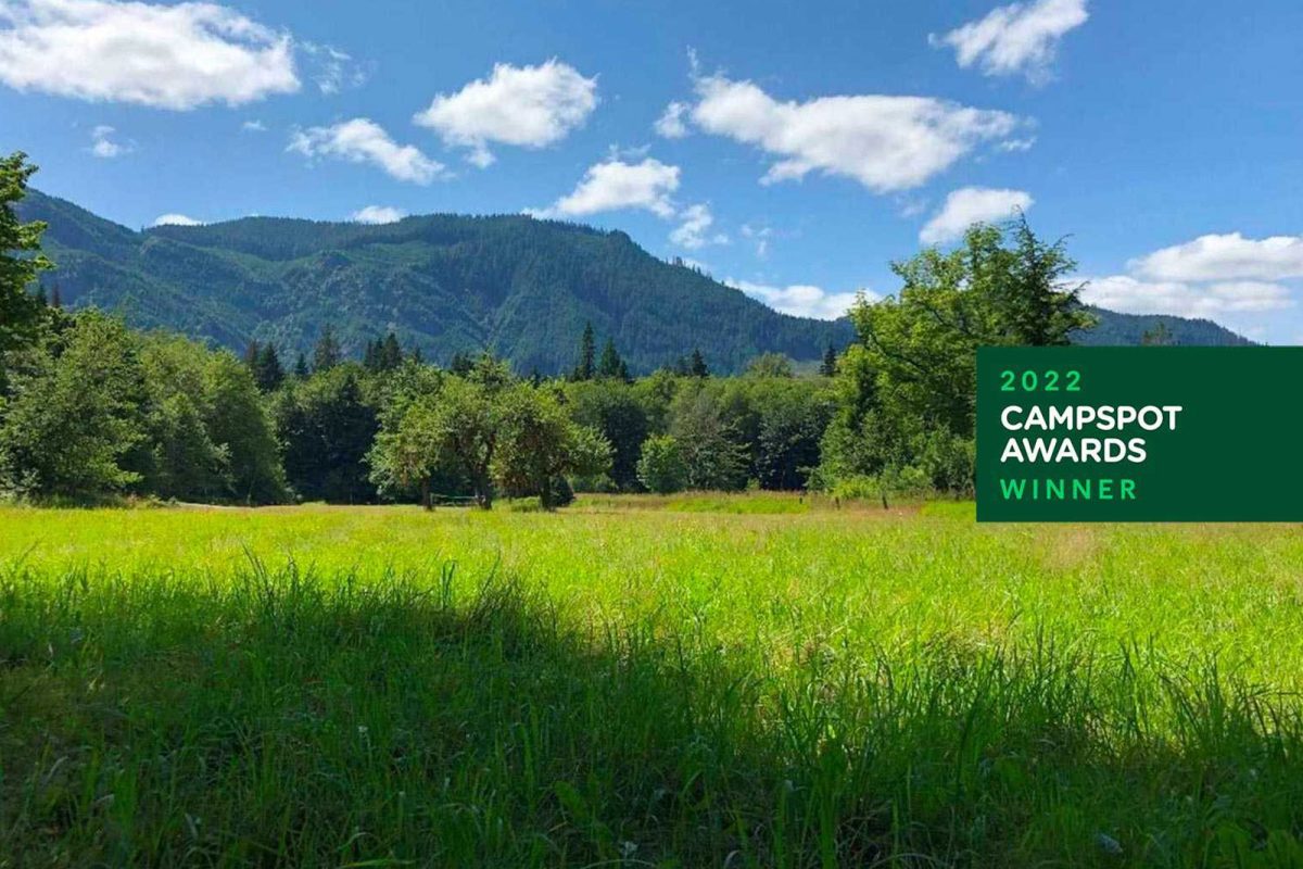 A meadow with mountains in the background and blue skies at Elkamp Eastcreek campground, a campground off the beaten path. 