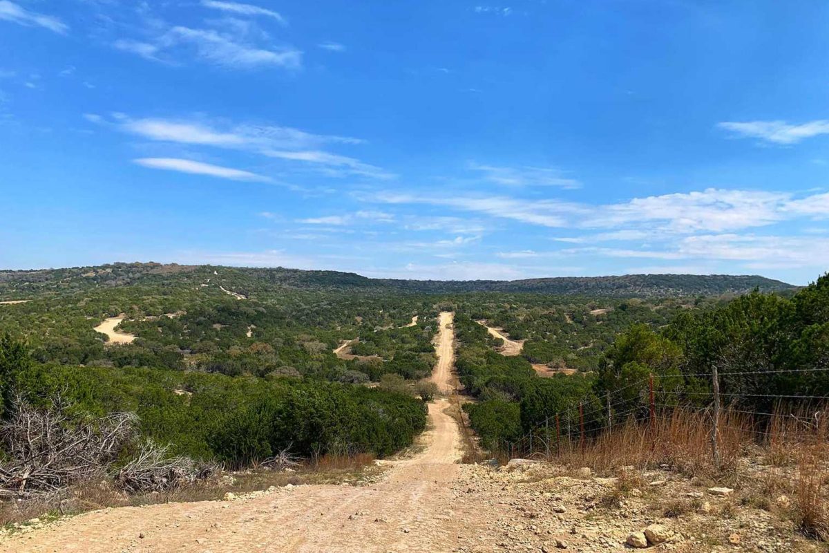 An off-roading trail cuts through brush with blue skies overhead at Hidden Falls Adventure Park. 