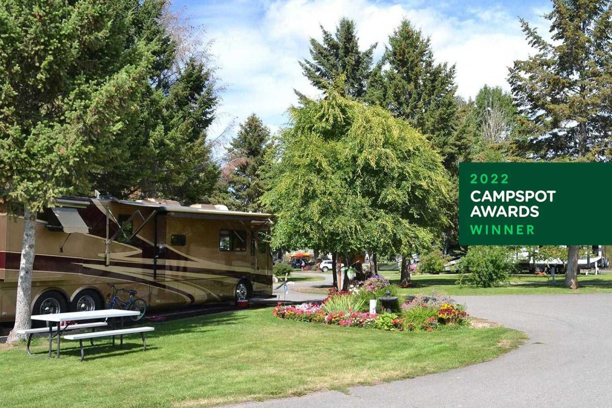 An RV parked between trees at Jim & Mary's RV Park. 