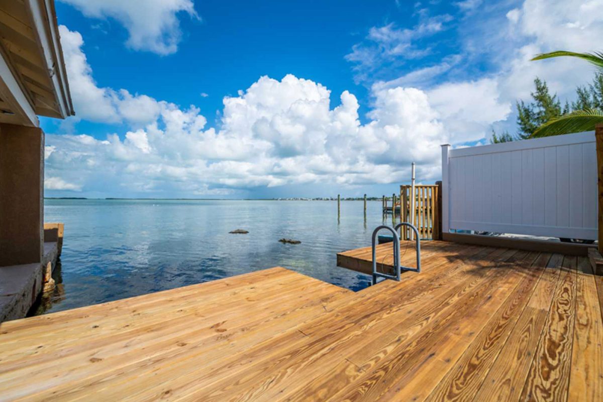 A dock at Sun Outdoors Key Largo overlooks the ocean with blue skies and clouds in the distance. 