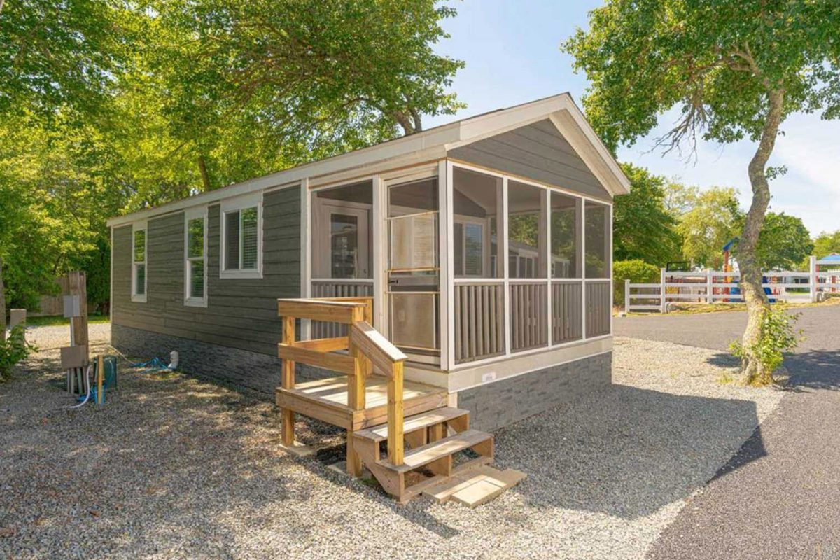 A grey cabin underneath trees at Sun Retreats Cape Cod. 