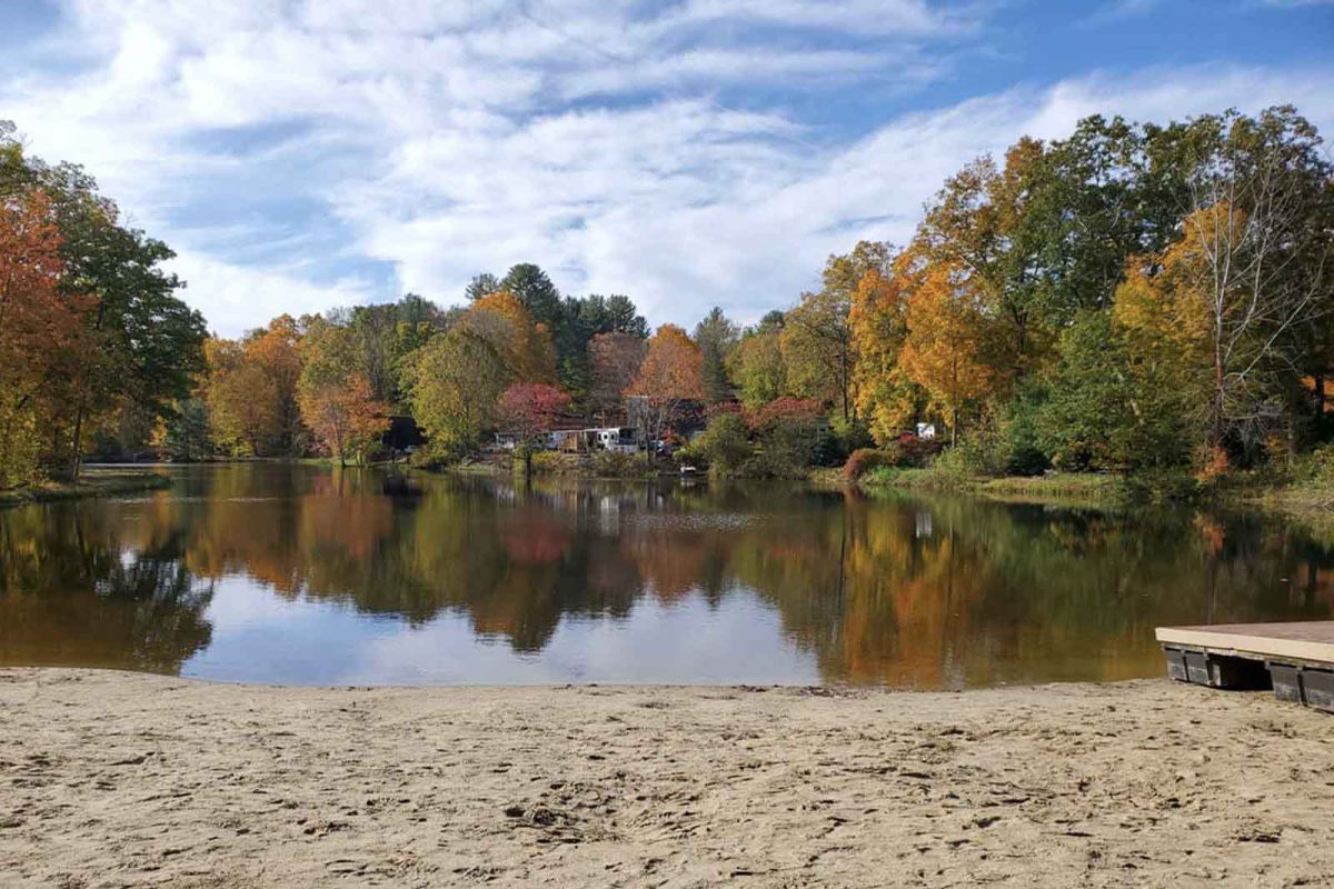 A body of water surrounded by changing leaves in New England. 