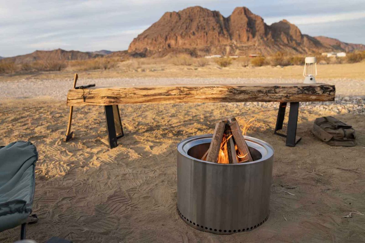 A fire pit and seating area in desert scenery with mountains in the background. 