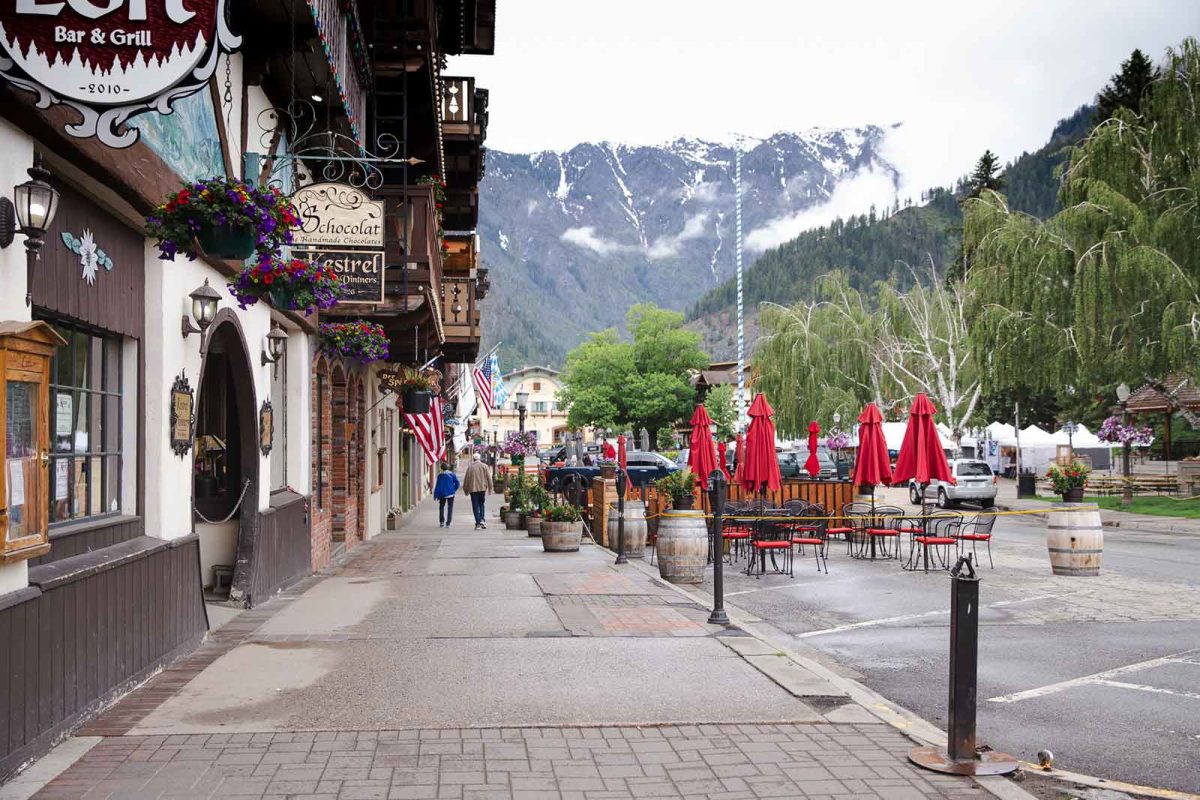 Shop signs hang from overhead a sidewalk in Leavenworth. 