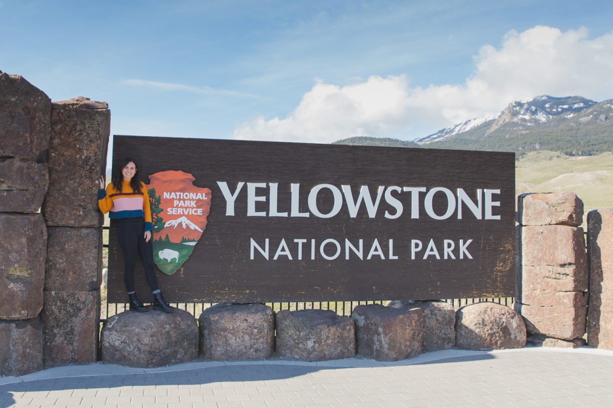 woman standing in front of Yellowstone National Park sign