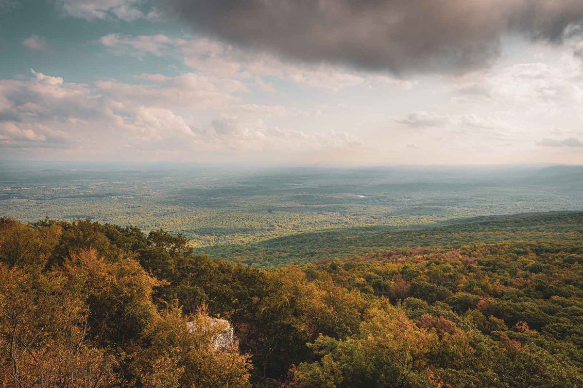 View from Sam's Point of the trees and fall foliage below with clouds in the distance 