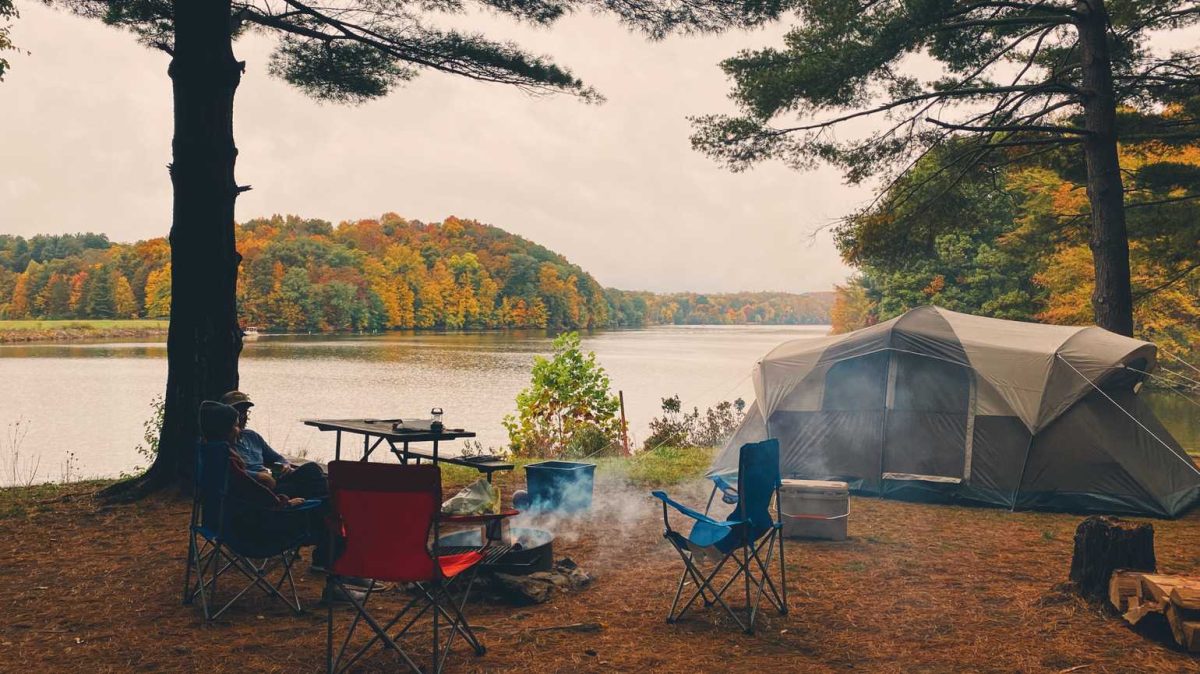 campers enjoying fire next to their tent and lake