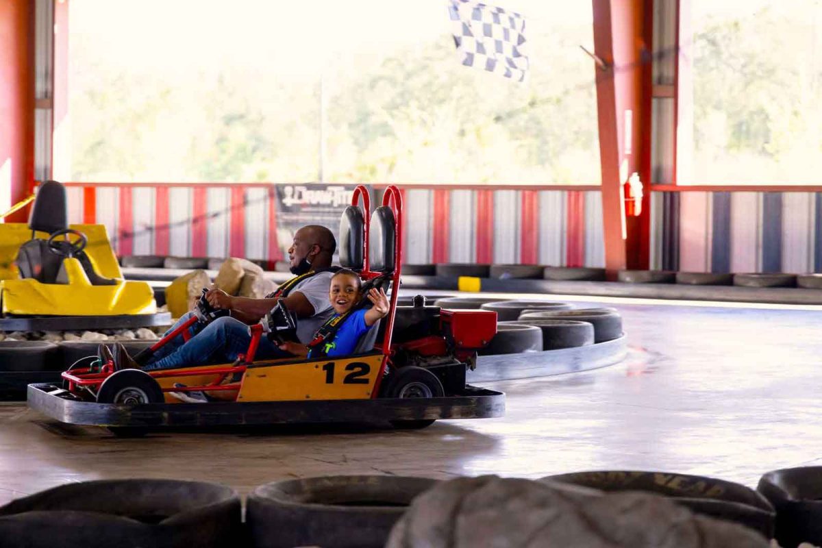 father and son go-carting, boy waving