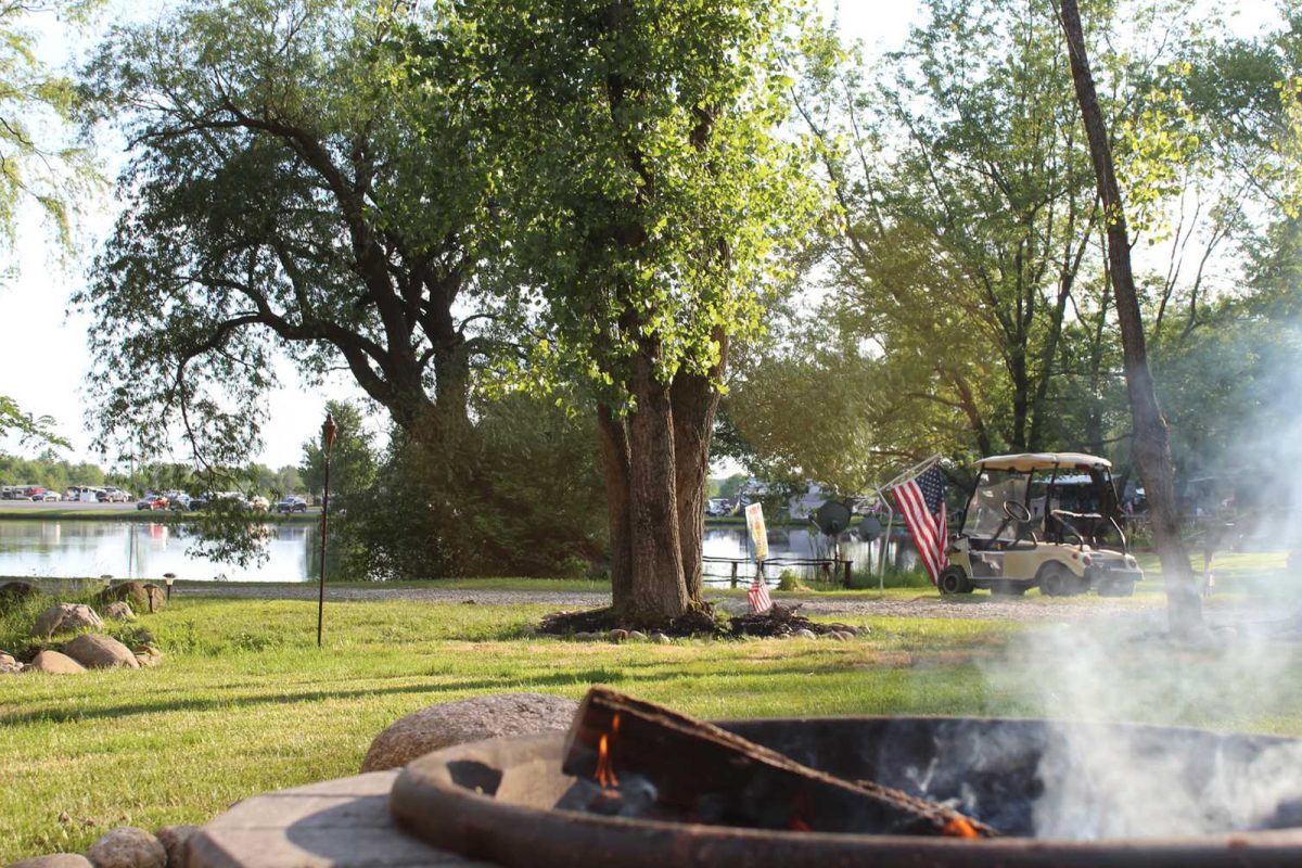 golf cart with American flag parked by fire pit on campground near NFL stadium