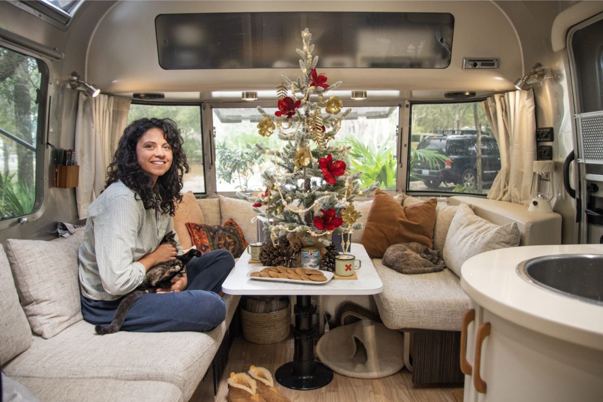 woman with cat sitting by mini Christmas tree inside RV