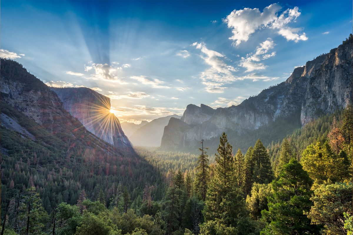 Sun peeking through mountains at Yosemite National Park, one of the best places to camp